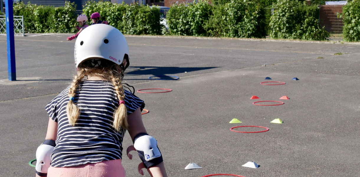 Une enfant en train de faire un parcours d'obstacle en patin à roulettes.