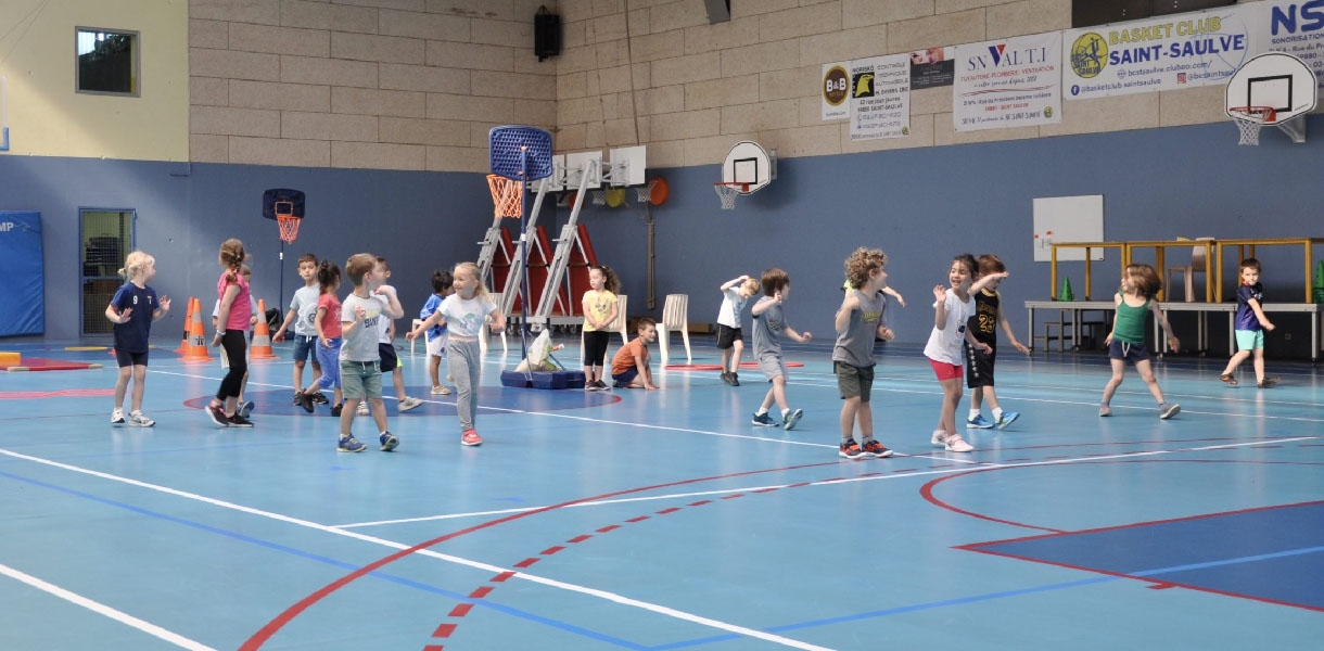Des enfants jouant au basket sur un terrain intérieur.
